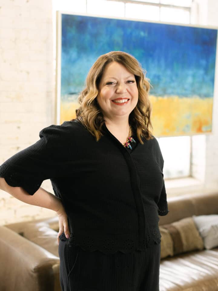 Smiling woman in black outfit at Kristen McGee Interiors conference.