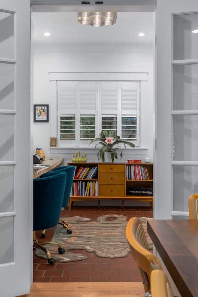 Modern home office with white walls and large windows.