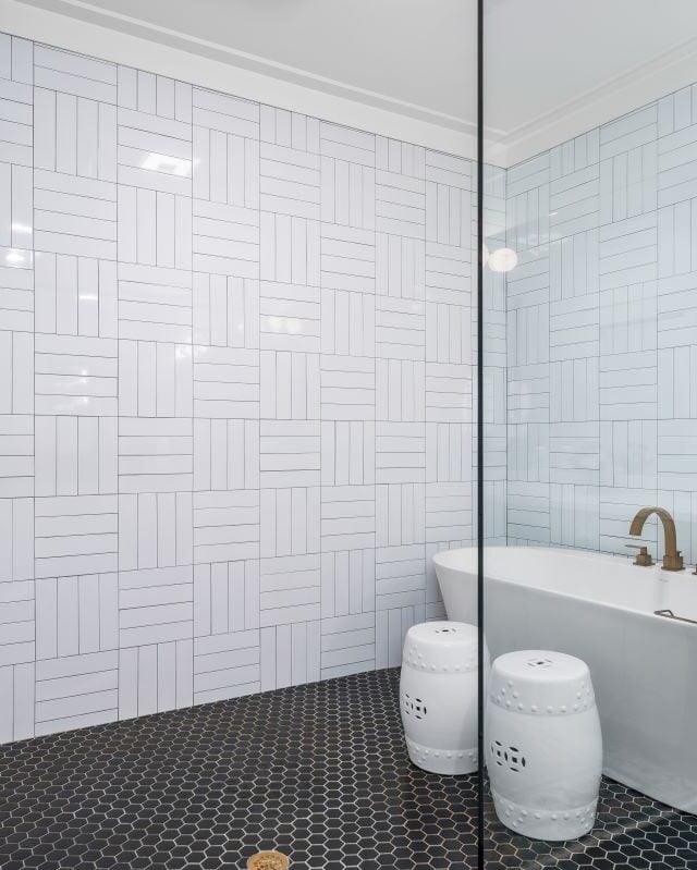 Modern bathroom with freestanding tub and sleek white tile walls.