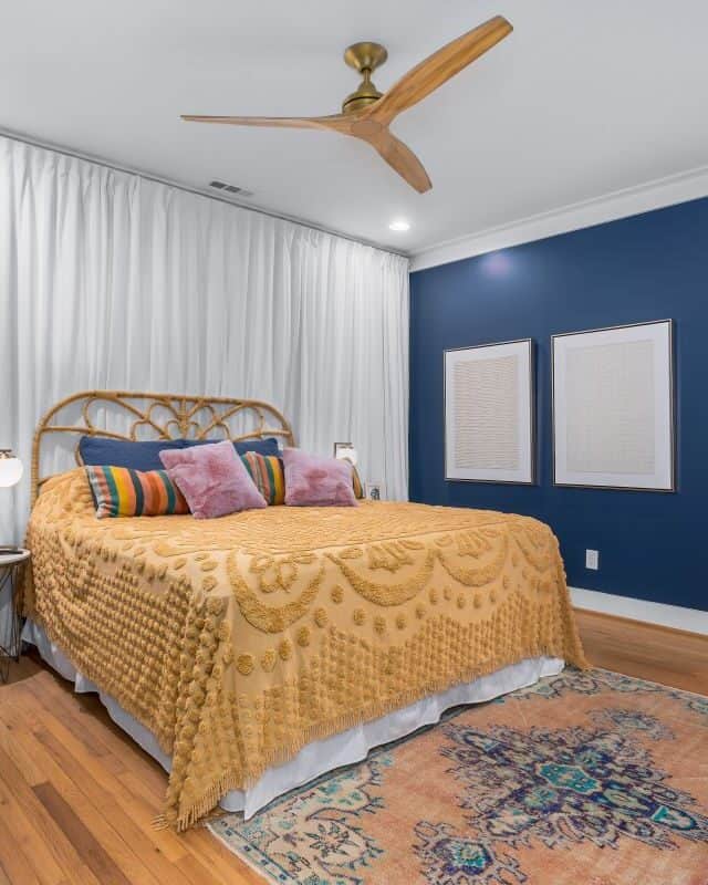 Modern bedroom with blue accent wall and wooden furniture.