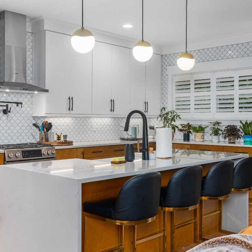 Bright kitchen featuring white cabinetry, black seating, and pendant lighting.