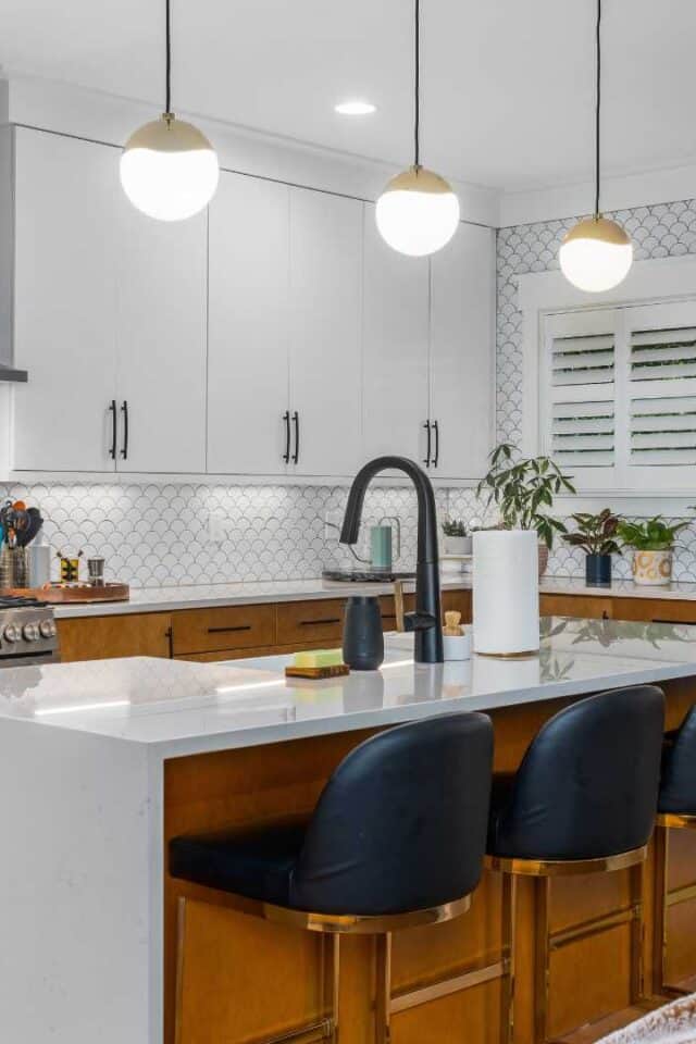 Bright kitchen featuring white cabinetry, black seating, and pendant lighting.