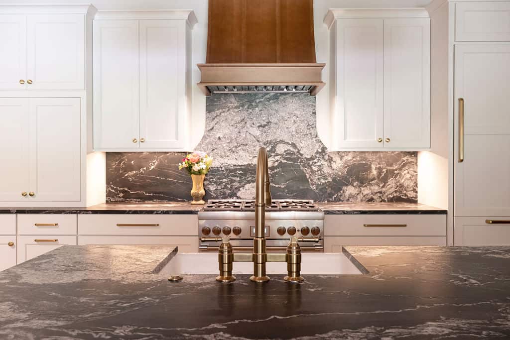 Modern kitchen with sleek white cabinets and a marble backsplash.