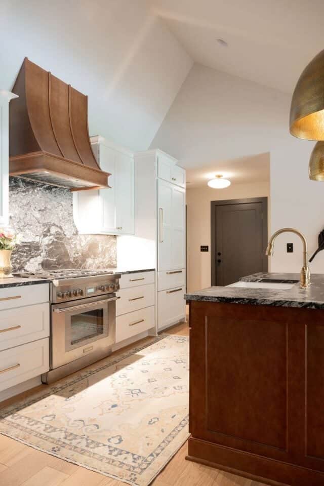 Bright kitchen featuring white cabinetry, marble countertops, and stylish lighting fixtures.