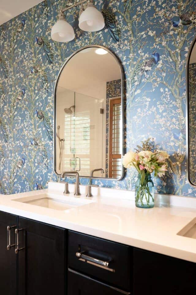 Elegant bathroom with blue floral wallpaper, mirrors, and modern fixtures.