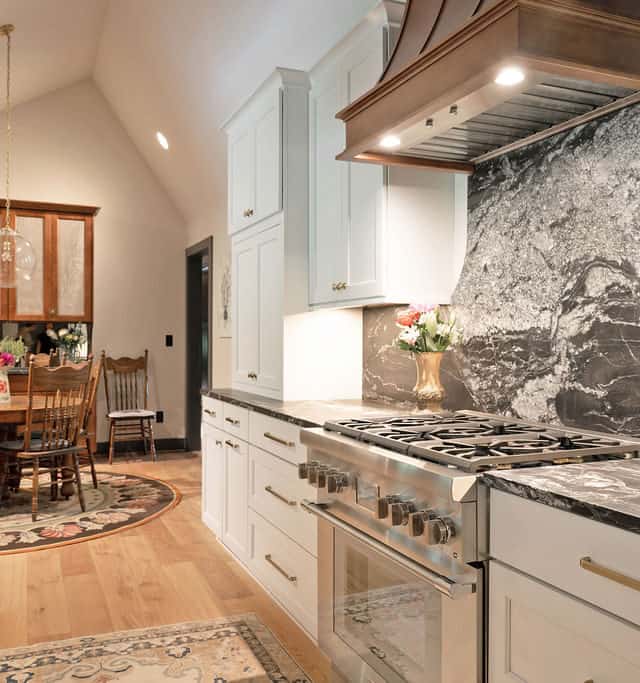 Bright, modern kitchen with white cabinets, marble backsplash, and stainless steel appliances.