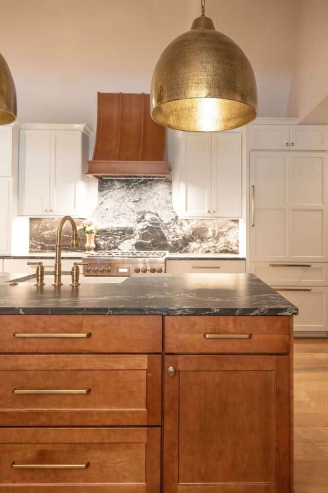 Beautiful renovated kitchen featuring a marble backsplash and stylish gold pendant lights.