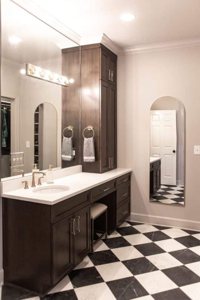 Elegant primary bathroom vanity with dark wood cabinetry and modern fixtures.