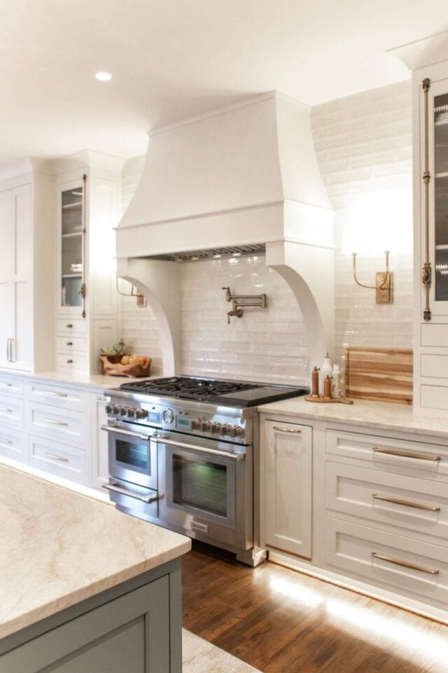 Modern white kitchen with a stylish range hood and stainless steel appliances.
