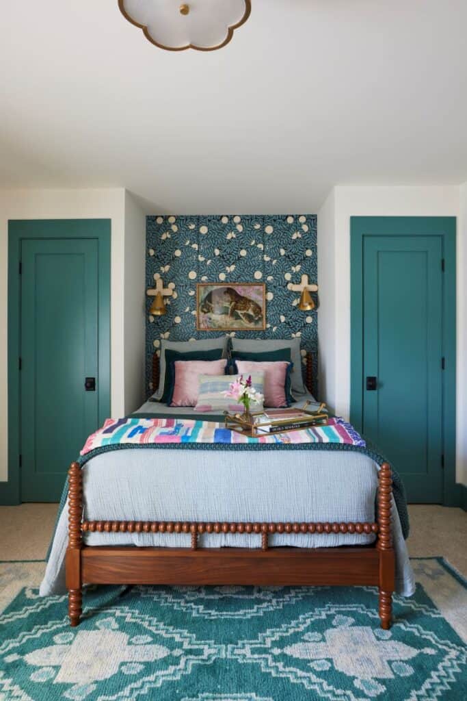 Inviting guest nook featuring a bed with colorful bedding and a patterned accent wall.