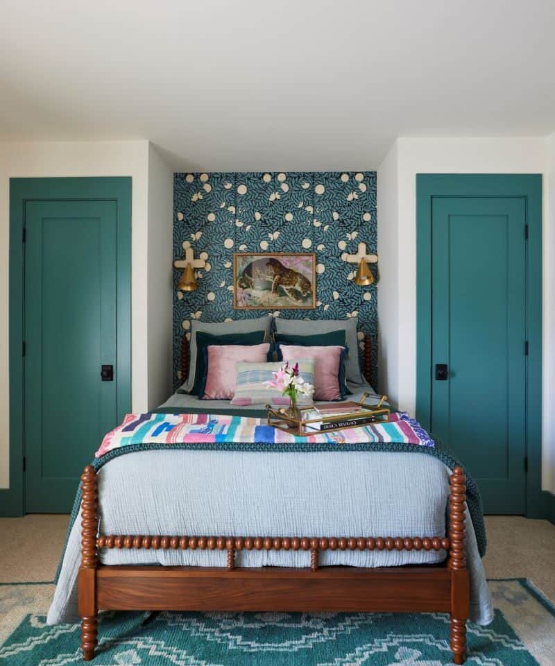 Inviting guest nook featuring a bed with colorful bedding and a patterned accent wall.