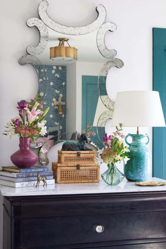 Elegant guest nook with stylish mirror and floral accents.