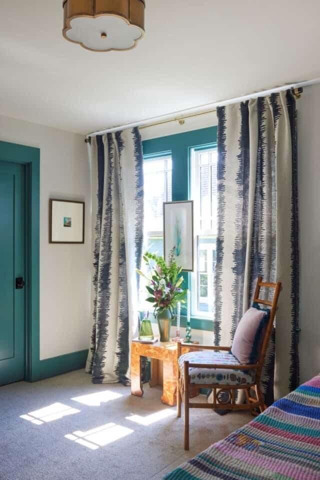 Cozy guest nook with vibrant curtains and a wooden chair for relaxing. Perfect for a welcoming 2024.