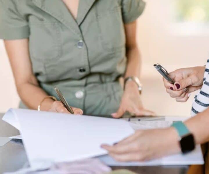 Two professionals collaborating over documents with smartphones and papers.