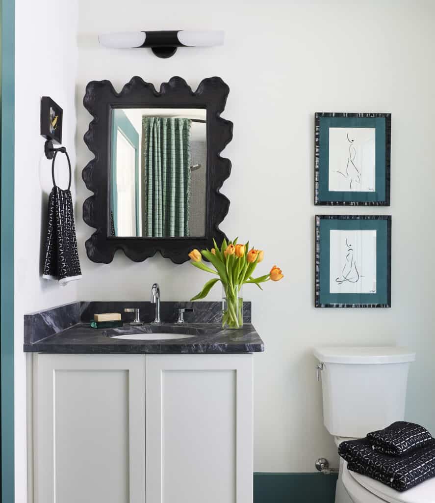Stylish guest bathroom with black-framed mirror, abstract art, and fresh tulips.