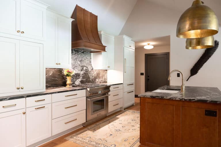 Bright, contemporary kitchen featuring white cabinetry, marble countertops, and stylish gold fixture.