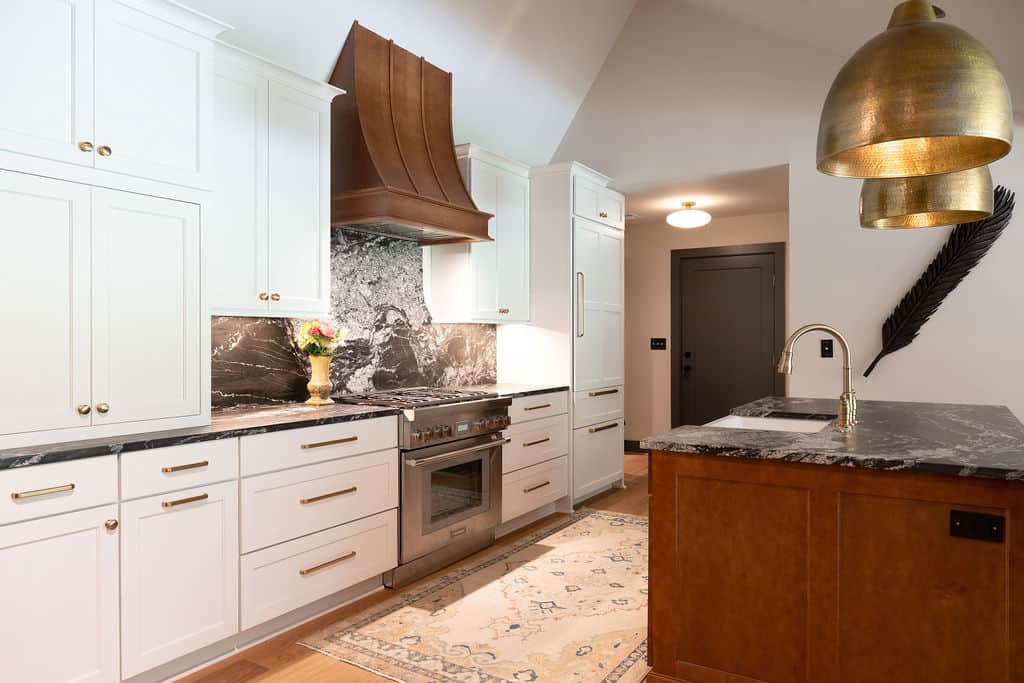 Bright, contemporary kitchen featuring white cabinetry, marble countertops, and stylish gold fixture.