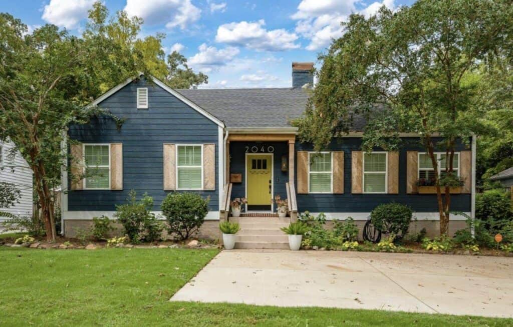 Beautiful blue house with white shutters and lush greenery in Birmingham.