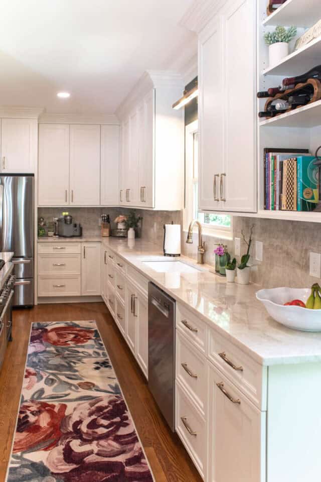 Modern white kitchen with open shelving and marble countertops.