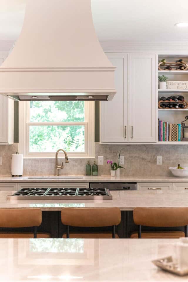 Bright kitchen with white cabinets, beige countertops, and a large window.